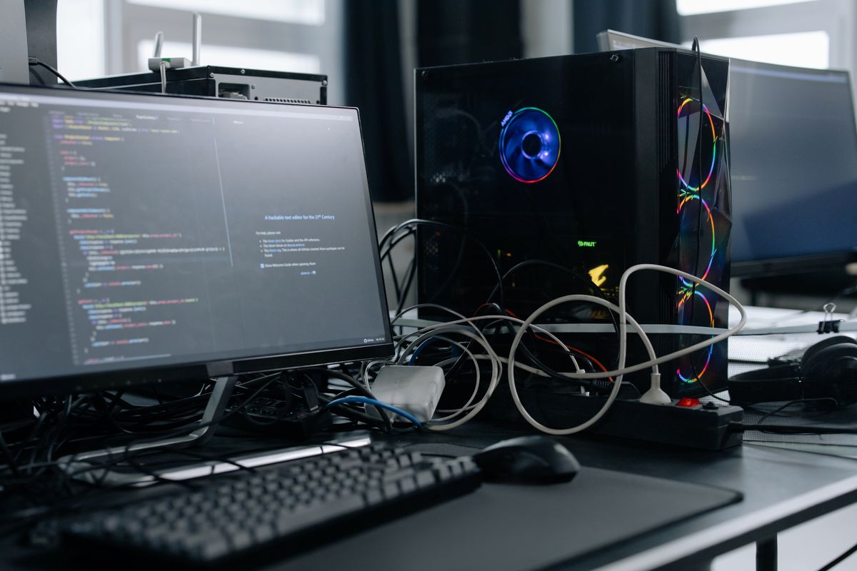 Monitor con código junto a una torre de PC
